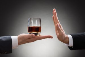 Close-up Of Businessman Hand Reject A Glass Of Whisky Offered By Businessperson