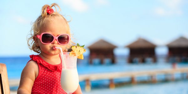 cute little girl drinking cocktail on tropical beach resort