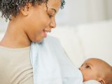 A mother is breastfeeding her little boy happily in their home.
