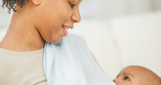 A mother is breastfeeding her little boy happily in their home.