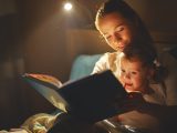 mother and child girl reading a book in bed before going to sleep